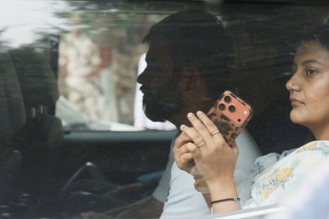 Abhijeet Dipke sits in a car as a woman beside him holds a phone to her ear