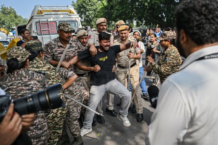 Police officers detain a protester during a demonstration in Delhi, Indi